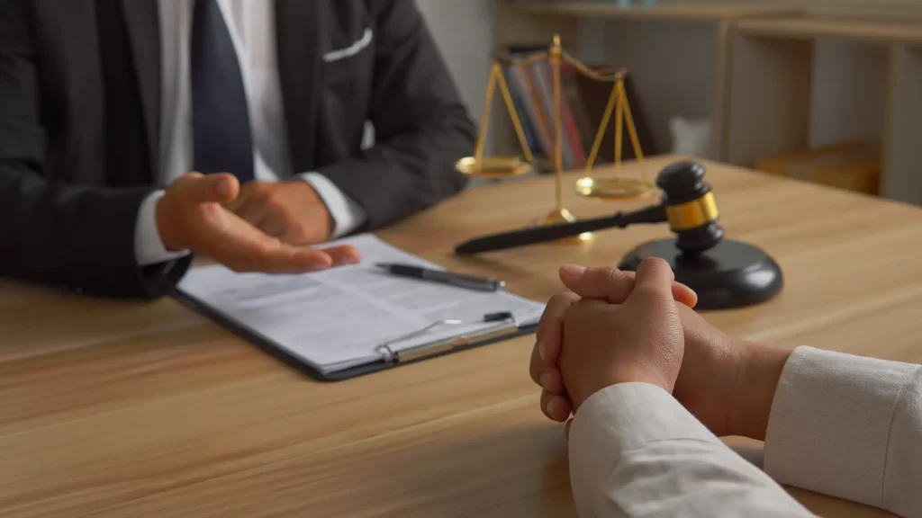 A lawyer and cilent discussing regulatory matters with a gavel and scale on the desk